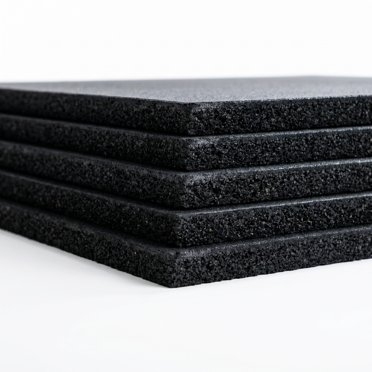 Stack of black rubber gym flooring mats showing side profile of thicknesses