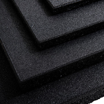 Corner close-up of black rubber gym tiles stacked in increasing thicknesses