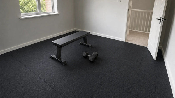 Spare room home gym floored with black 1 m rubber tiles, with a flat bench and a pair of hex dumbbells