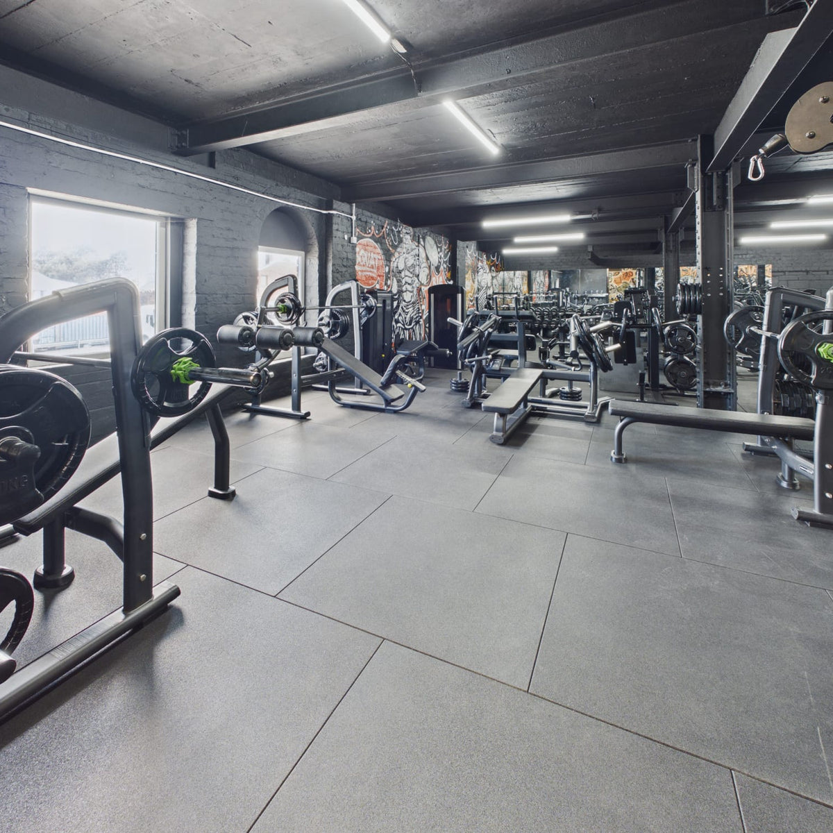Commercial gym with black rubber gym flooring and free-weight equipment